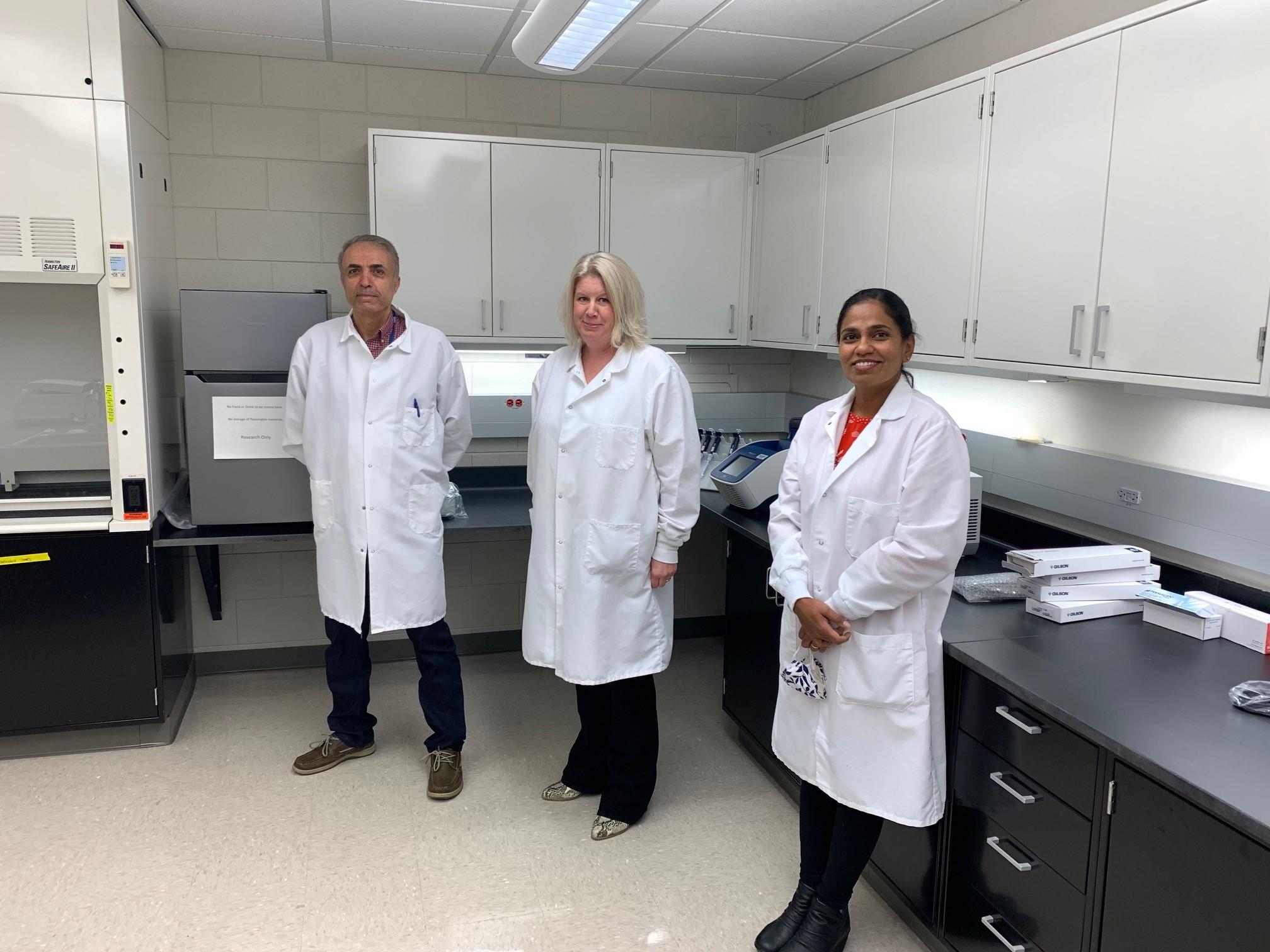 Three lab members in white coats