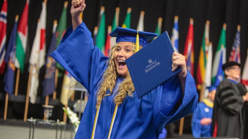 A graduate celebrates with their diploma